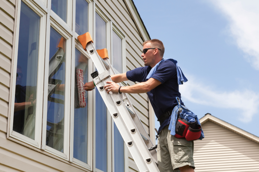 worker on a ladder cleaning windows