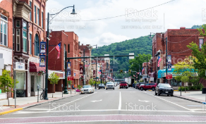 town with red buildings and trees in the background and cars driving on road